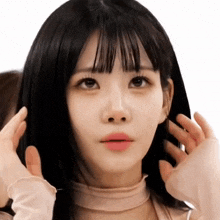 a close up of a woman 's face with her hands on her head
