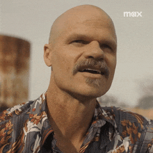 a man with a mustache is wearing a shirt with a max logo on the bottom