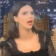 a close up of a woman with her mouth open wearing a black dress .