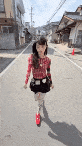 a young girl is walking down a street wearing red shoes