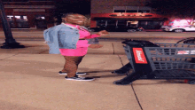 a woman in a pink dress is standing next to a shopping cart that says schnuck 's on it