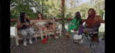 a group of women are sitting on a couch on a deck talking .