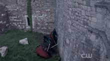 a person is climbing a brick wall with a cw logo in the corner .
