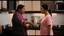 a woman in a pink shirt is talking to another woman