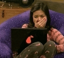 a woman is sitting on a purple chair using a laptop computer .