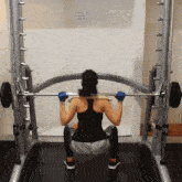 a woman squatting with a barbell in front of a sign that says " do not use "