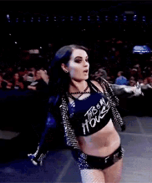 a woman is standing in a wrestling ring wearing a black jacket and shorts .