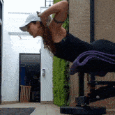 a woman wearing a white hat is doing push ups on a purple mat