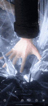 a person 's hand is visible through a broken glass