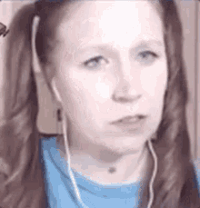a close up of a woman wearing headphones and a blue shirt .