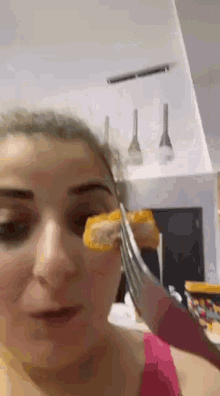 a woman is holding a piece of food in front of her face with a pair of scissors .