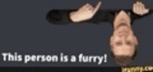 a man laying upside down with the words " this person is a furry " above him