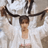 a woman is wearing a white jacket and holding her hair in pigtails .