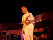 a man in white playing a guitar on stage