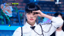 a girl in a white shirt stands on a stage in front of a screen that says mnet