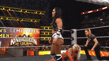 a woman in a wrestling ring with a sign that says ' king queen of the ring '
