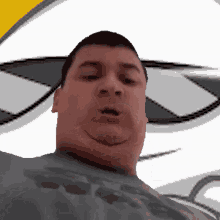 a man wearing a gray shirt with the letter r on it looks at the camera