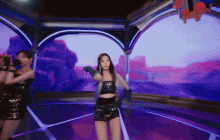 two women are dancing on a stage in front of a purple screen .