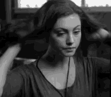 a black and white photo of a woman holding her hair in her hand .