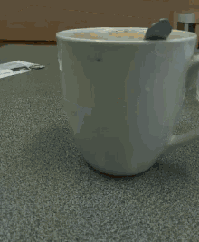 a cup of coffee is sitting on a table next to an envelope with a picture of a man on it