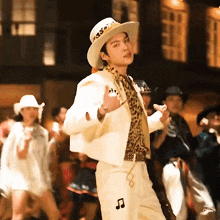 a man wearing a cowboy hat is dancing in front of a crowd .