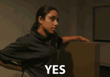 a woman in a blue shirt says yes in front of a cabinet