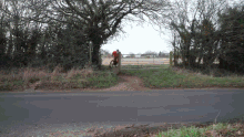 a man in a red shirt is riding a bike down a dirt road
