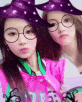 two girls wearing glasses and witch hats are posing for a picture together .