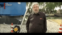 a man is standing in front of a blue boat with the words rtv utrecht on the bottom