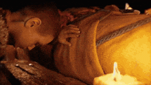 a person wrapped in a blanket with a candle in the background