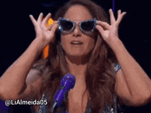a woman wearing sunglasses is standing in front of a microphone with the hashtag lialmeida05