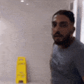 a man is standing in front of a yellow sign that says " caution wet floor "