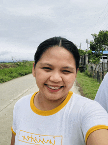 a woman wearing a white t-shirt with a yellow border smiles