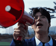 a man in a suit is holding a red megaphone with the letter g on it