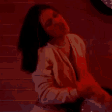 a woman in a yellow jacket is dancing in a dark room with red lights .