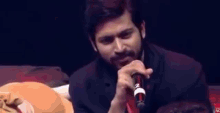 a man with a beard is singing into a microphone with the word nc on the bottom