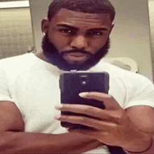 a man with a beard is taking a selfie in a bathroom .
