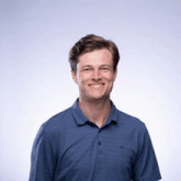 a young man wearing a blue shirt is smiling for the camera