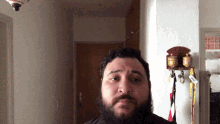 a man with a beard is standing in front of a wall with a shelf full of boxes of cigarettes