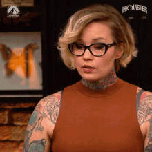 a woman wearing glasses stands in front of a paramount sign that says ink master