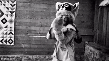 a black and white photo of a man in a raccoon costume holding a baby .
