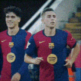two soccer players wearing red and blue jerseys with spotify logos on them