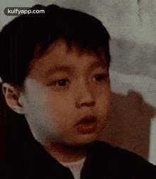 a young boy is making a funny face and looking at the camera .