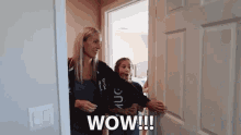 a woman and a girl are standing in a doorway with the words wow written on the door