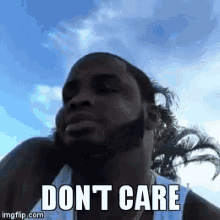 a man with a beard is wearing a white tank top and says don t care .