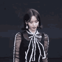 a woman wearing a black and white dress with a bow on her neck .