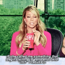 a woman in a pink shirt is holding a coca cola can in her hands