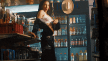 a woman in a cowboy hat stands in front of a refrigerator full of soda