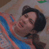a blurry picture of a person laying on a bed with a striped blanket .