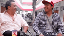 two men are sitting next to each other and one of them has a red hat on